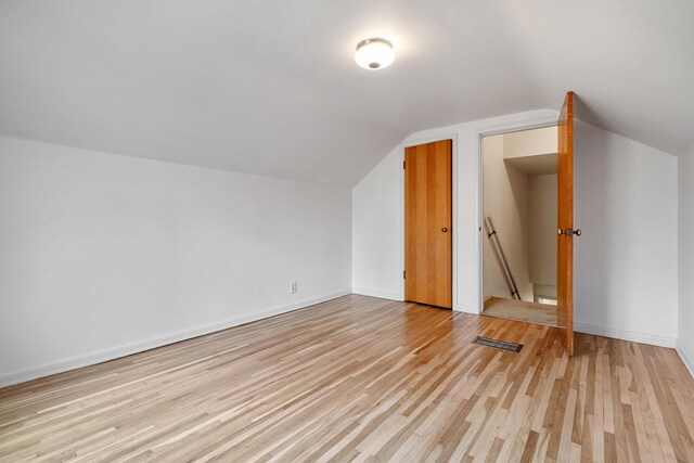 additional living space with light hardwood / wood-style flooring and vaulted ceiling