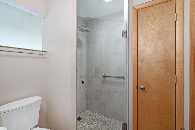 bathroom with a shower with shower door and toilet