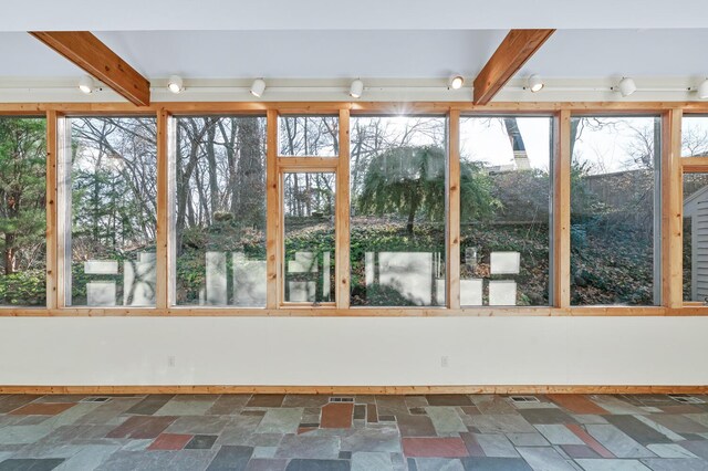 unfurnished sunroom featuring beam ceiling