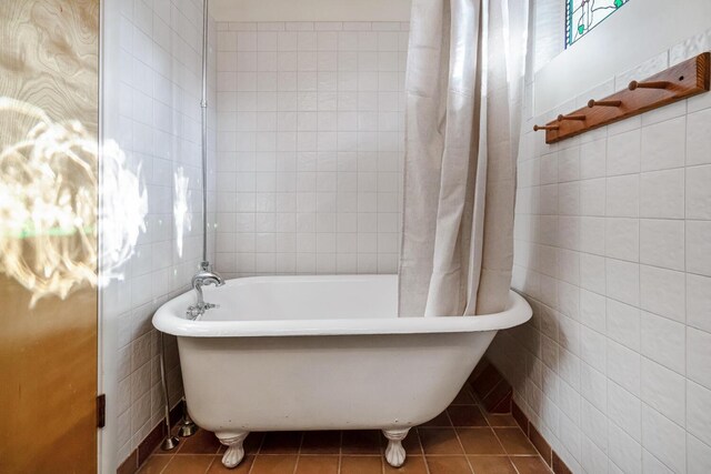 bathroom with tile patterned flooring, a tub to relax in, and tile walls