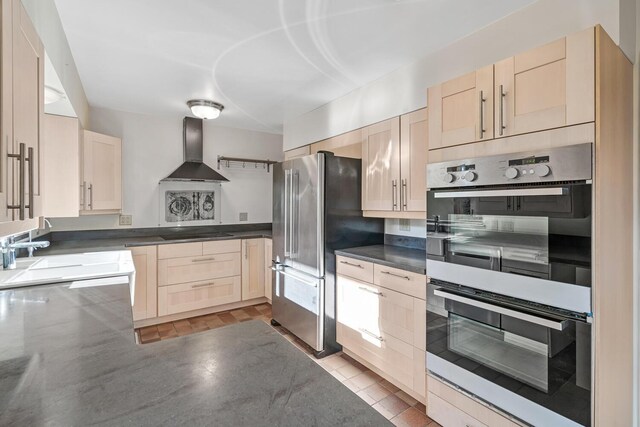 kitchen with light brown cabinetry, sink, wall chimney exhaust hood, and stainless steel appliances