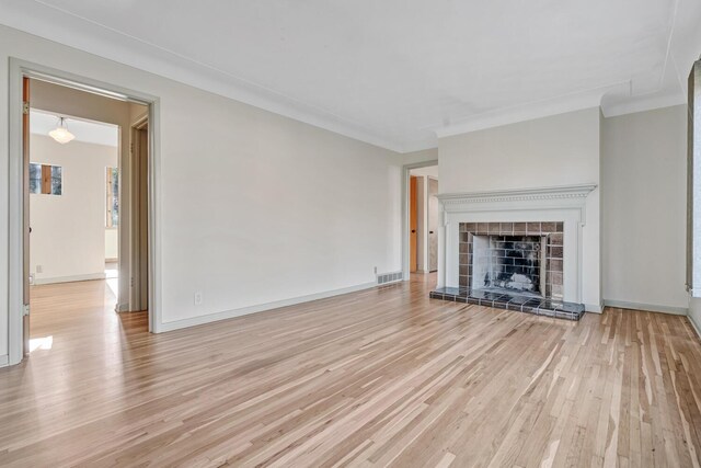 unfurnished living room with a tile fireplace and light hardwood / wood-style flooring