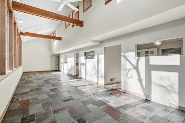 empty room featuring beamed ceiling, high vaulted ceiling, and ceiling fan