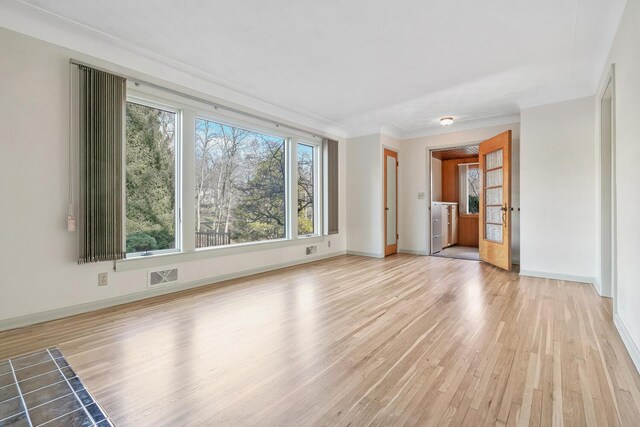 unfurnished living room with ornamental molding and light wood-type flooring