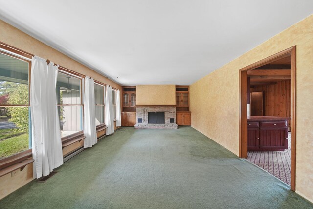 unfurnished living room with dark carpet and a brick fireplace