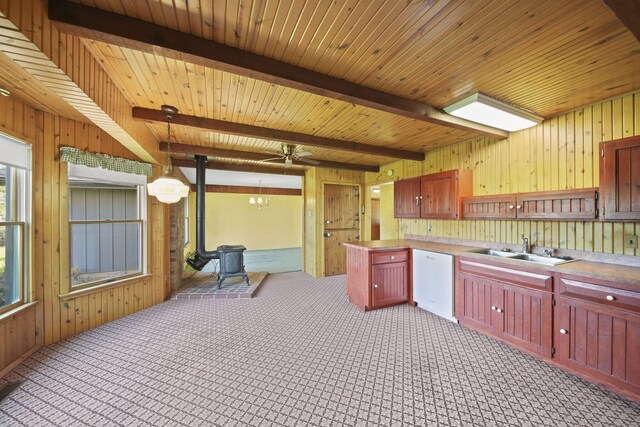 kitchen with beamed ceiling, sink, dishwasher, and a wood stove