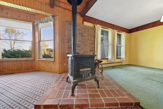 unfurnished living room featuring carpet flooring, a wood stove, beam ceiling, and wooden walls