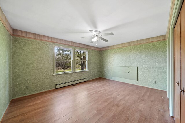 unfurnished room featuring light hardwood / wood-style floors, a baseboard heating unit, and ceiling fan