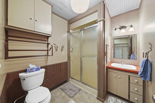 bathroom featuring vanity, wooden walls, toilet, and walk in shower