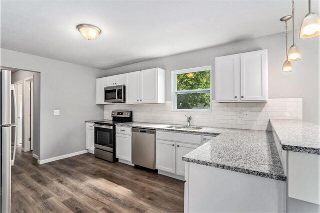 kitchen featuring appliances with stainless steel finishes, white cabinets, decorative light fixtures, sink, and dark wood-type flooring