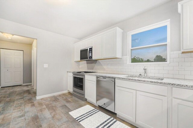 kitchen featuring sink, stainless steel appliances, white cabinetry, and backsplash