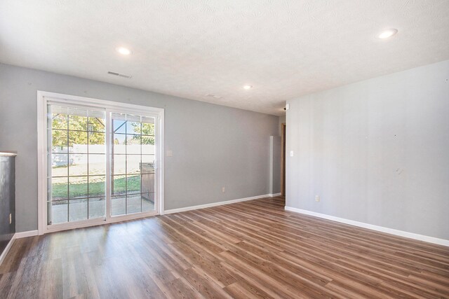 spare room with a textured ceiling and hardwood / wood-style flooring