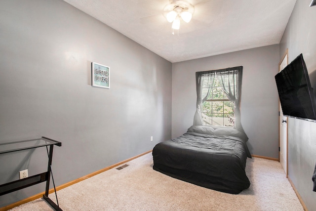 bedroom with light carpet, a textured ceiling, and ceiling fan