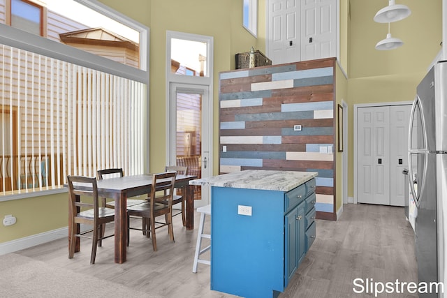 kitchen with stainless steel refrigerator, a center island, hanging light fixtures, a kitchen breakfast bar, and blue cabinets