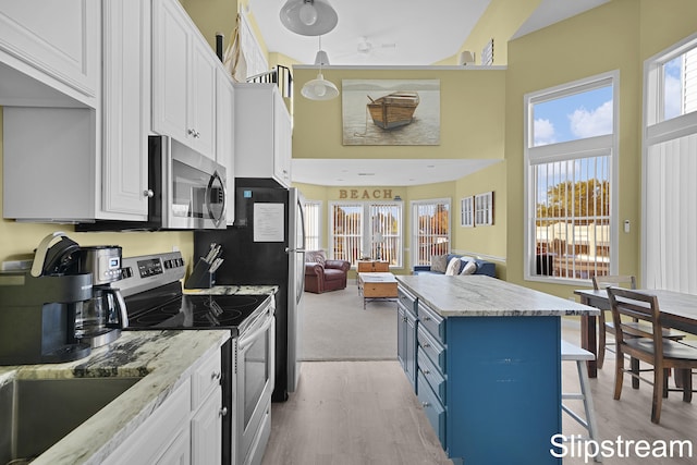 kitchen featuring stainless steel appliances, blue cabinets, a breakfast bar area, white cabinets, and light wood-type flooring