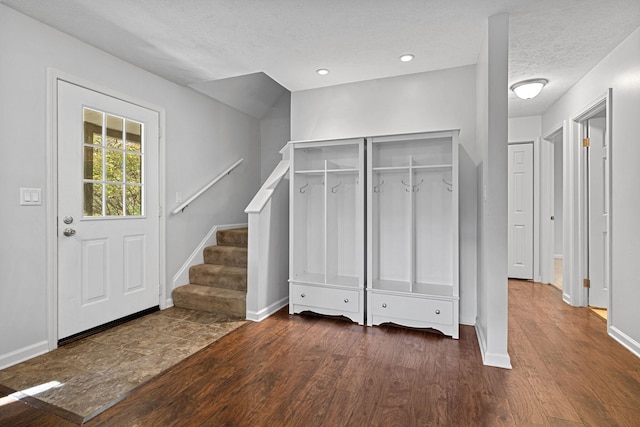 entryway with dark wood-type flooring and a textured ceiling