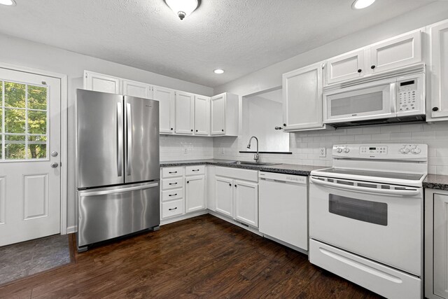 kitchen with white appliances, sink, white cabinets, dark wood-type flooring, and decorative backsplash