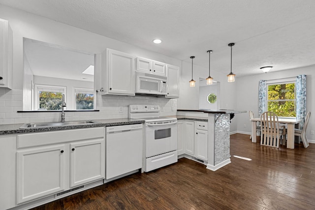 kitchen with kitchen peninsula, white cabinets, a wealth of natural light, sink, and white appliances