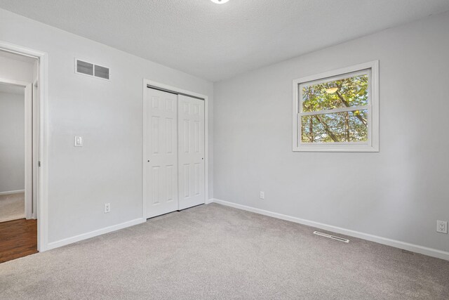 unfurnished bedroom with carpet, a textured ceiling, and a closet