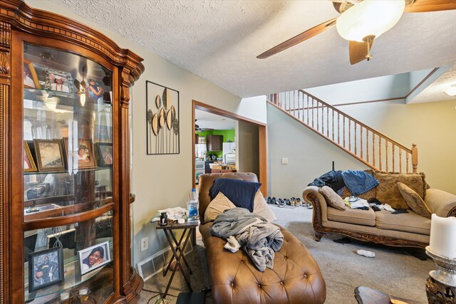 carpeted living room with ceiling fan and a textured ceiling