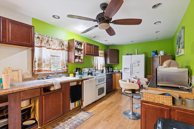 kitchen with sink, light stone countertops, light wood-type flooring, white appliances, and ceiling fan