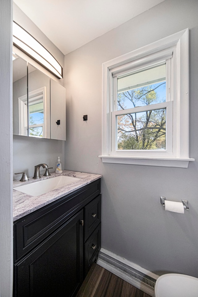 bathroom with baseboard heating, vanity, hardwood / wood-style flooring, and toilet