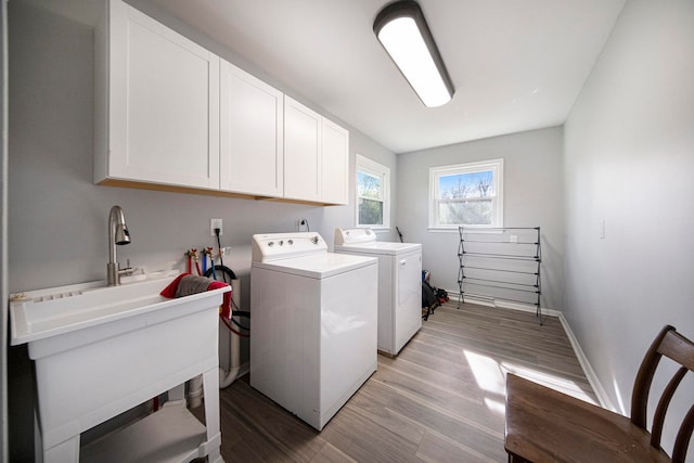 clothes washing area with washer and dryer, cabinets, and light hardwood / wood-style floors