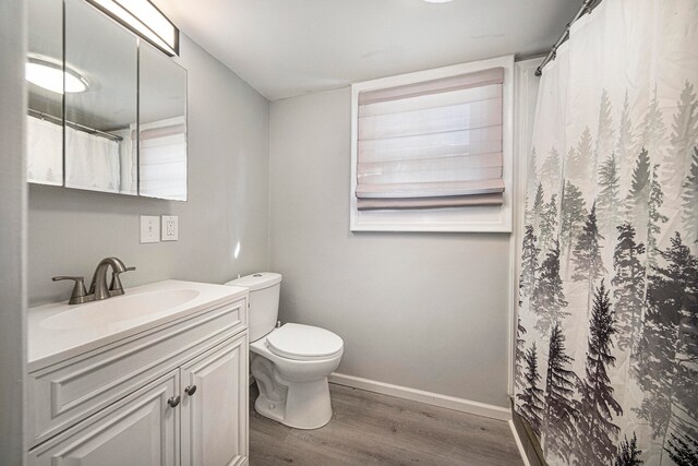 bathroom with vanity, toilet, curtained shower, and hardwood / wood-style floors