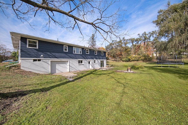 back of property with a yard, a trampoline, and a garage