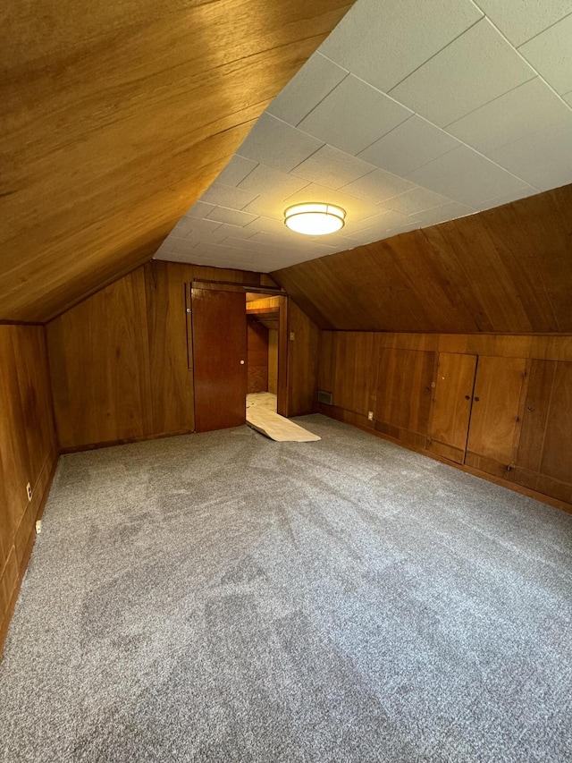 bonus room featuring lofted ceiling, wood walls, and light colored carpet