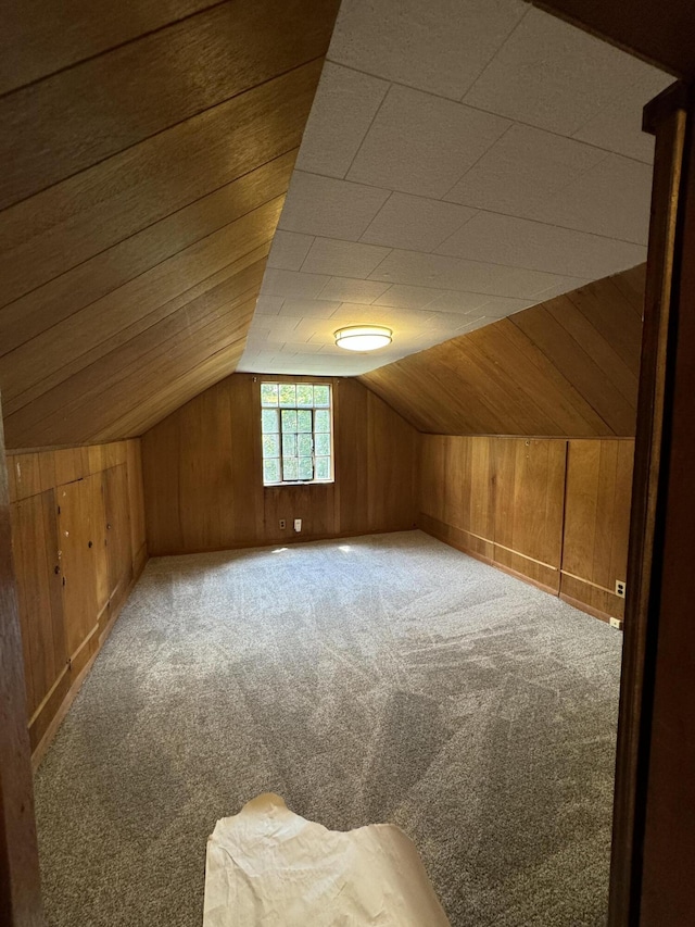 additional living space featuring lofted ceiling, wooden walls, and carpet floors