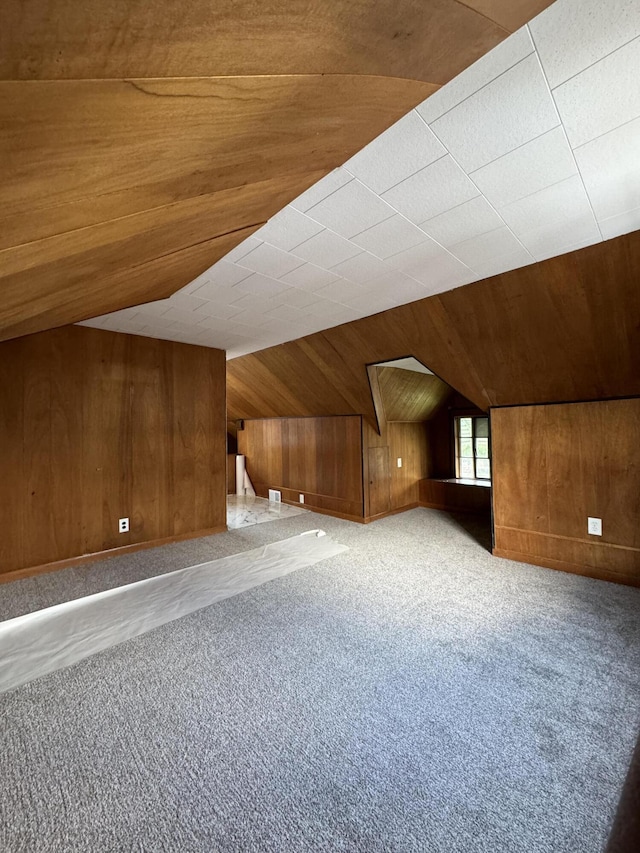 additional living space featuring lofted ceiling, wooden walls, and light colored carpet