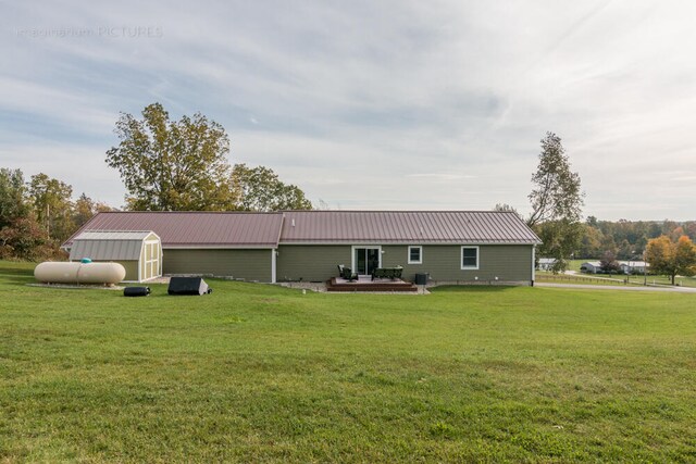 rear view of property with a storage unit and a lawn