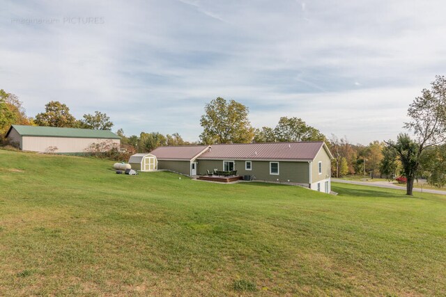 rear view of property with a yard and a storage shed