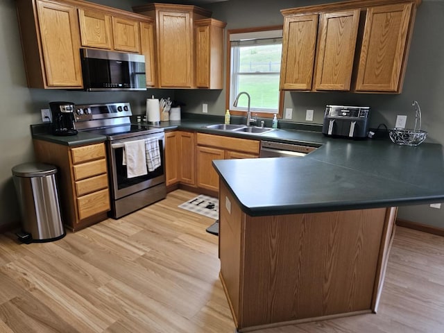 kitchen featuring sink, light hardwood / wood-style flooring, kitchen peninsula, and stainless steel appliances