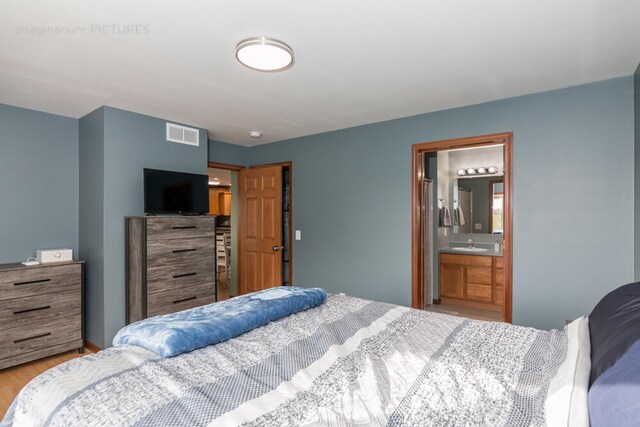 bedroom featuring connected bathroom and light wood-type flooring