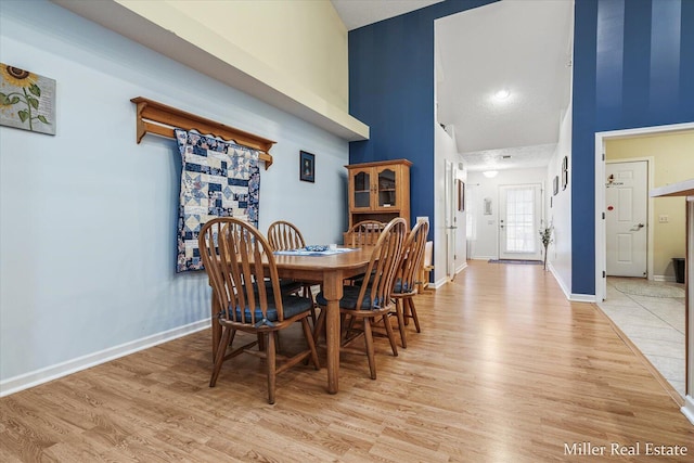 dining area with light wood-type flooring and high vaulted ceiling