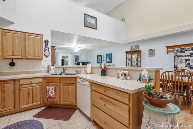 kitchen featuring kitchen peninsula, light tile patterned floors, sink, and dishwasher