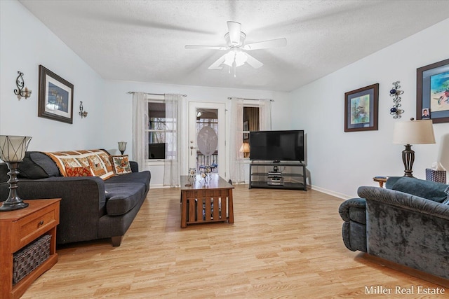 living room with a textured ceiling, light hardwood / wood-style flooring, and ceiling fan