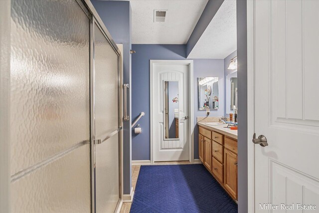 bathroom featuring vanity, a textured ceiling, and a shower with door