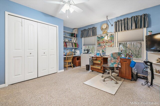 carpeted home office with built in desk and ceiling fan