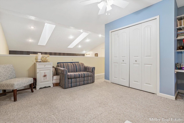 sitting room with vaulted ceiling with skylight, light colored carpet, and ceiling fan