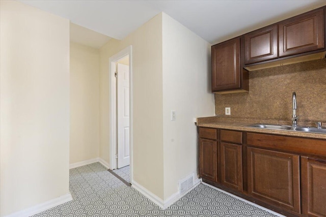 kitchen with backsplash, dark brown cabinets, and sink