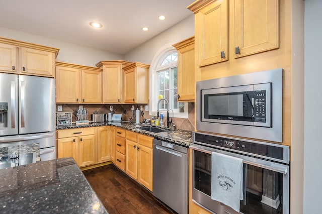 kitchen featuring light brown cabinetry, stainless steel appliances, sink, and dark stone counters