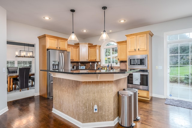 kitchen featuring backsplash, stainless steel appliances, light brown cabinets, and a kitchen island