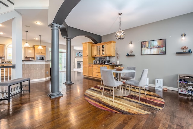 dining area with ornate columns and dark hardwood / wood-style flooring