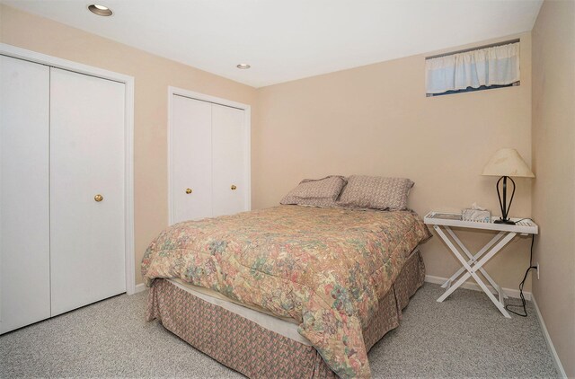 bedroom featuring light carpet and two closets