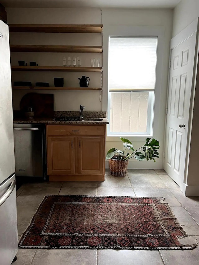 interior space featuring sink, dark stone counters, and dishwasher