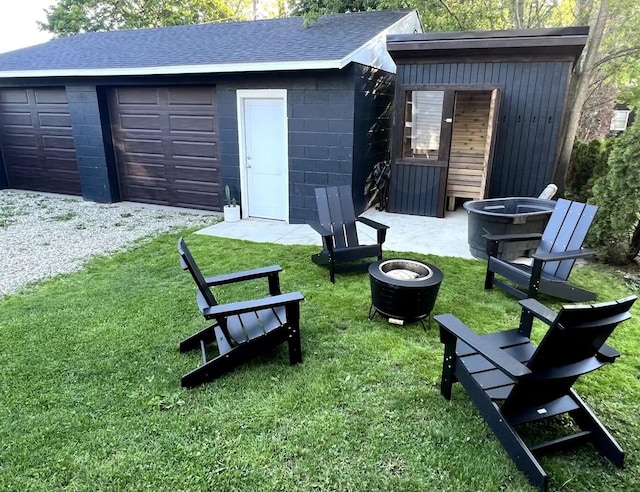 exterior space with an outdoor fire pit, a garage, and a lawn