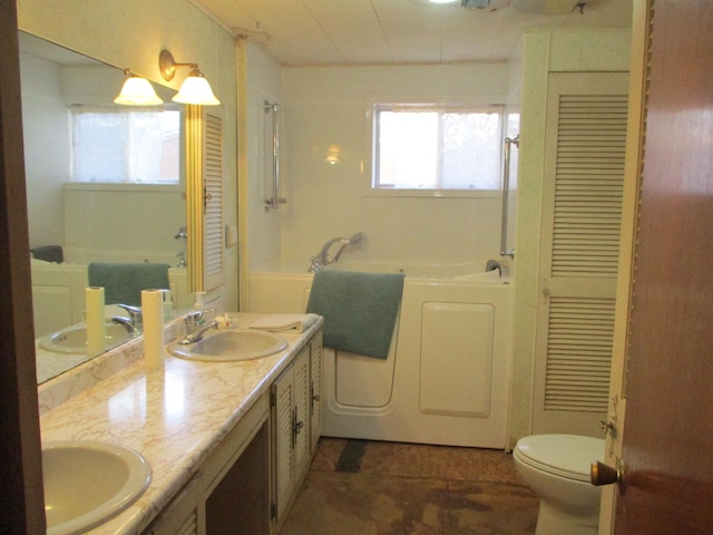 bathroom with vanity, toilet, a tub to relax in, and washing machine and clothes dryer